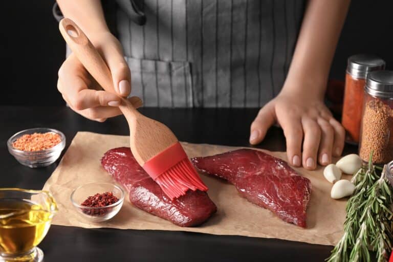 femme utilise pinceau de cuisine sur viande